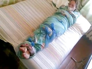 Barefoot girl mummified in a bedsheet