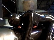 couple in black latex catsuit mask and the blowjob girl 